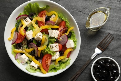 Photo of Delicious fresh Greek salad served on black table, flat lay