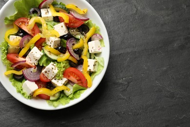 Photo of Delicious fresh Greek salad in bowl on black table, top view. Space for text