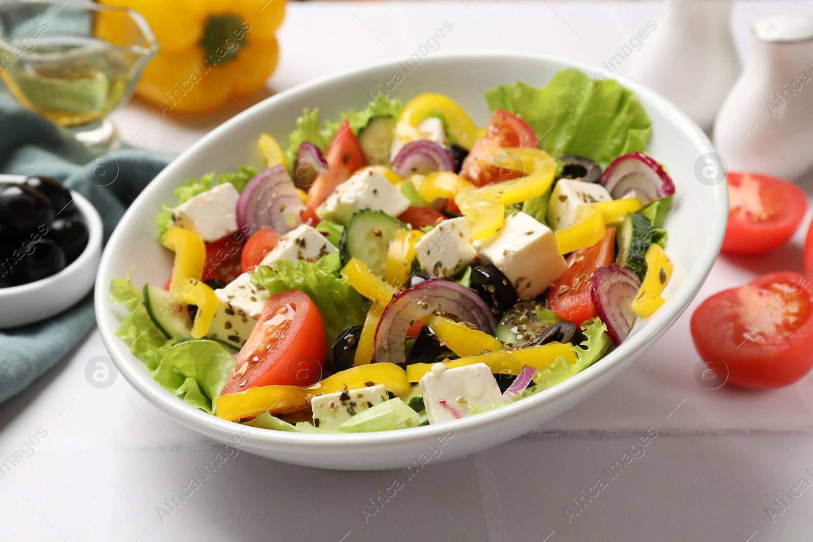 Photo of Delicious fresh Greek salad served on white tiled table, closeup