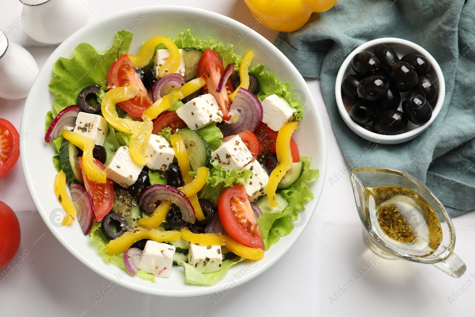 Photo of Delicious fresh Greek salad served on white tiled table, flat lay