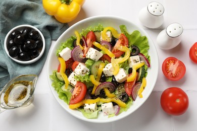 Photo of Delicious fresh Greek salad served on white tiled table, flat lay