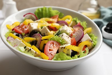 Photo of Delicious fresh Greek salad in bowl on white table, closeup