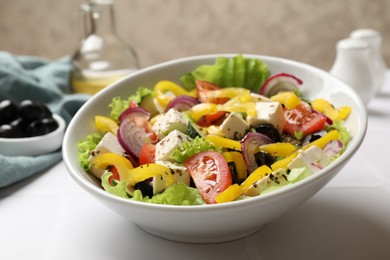 Photo of Delicious fresh Greek salad in bowl on white table, closeup