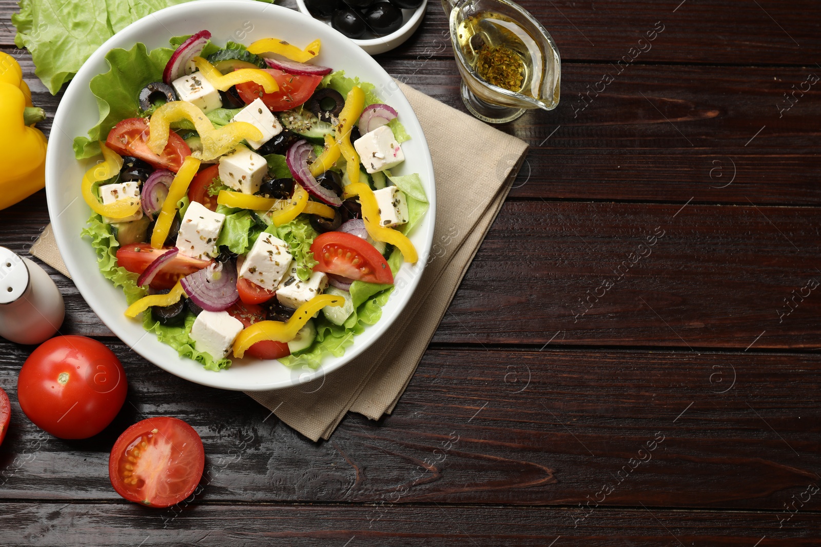 Photo of Delicious fresh Greek salad served on wooden table, flat lay. Space for text