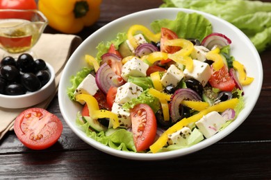 Photo of Delicious fresh Greek salad served on wooden table, closeup