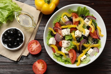 Photo of Delicious fresh Greek salad served on wooden table, flat lay