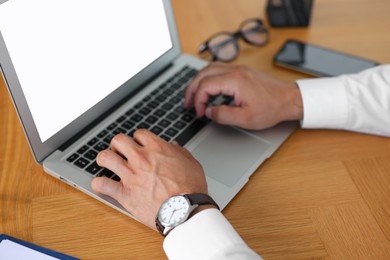 Photo of Office worker typing on laptop at wooden table, closeup