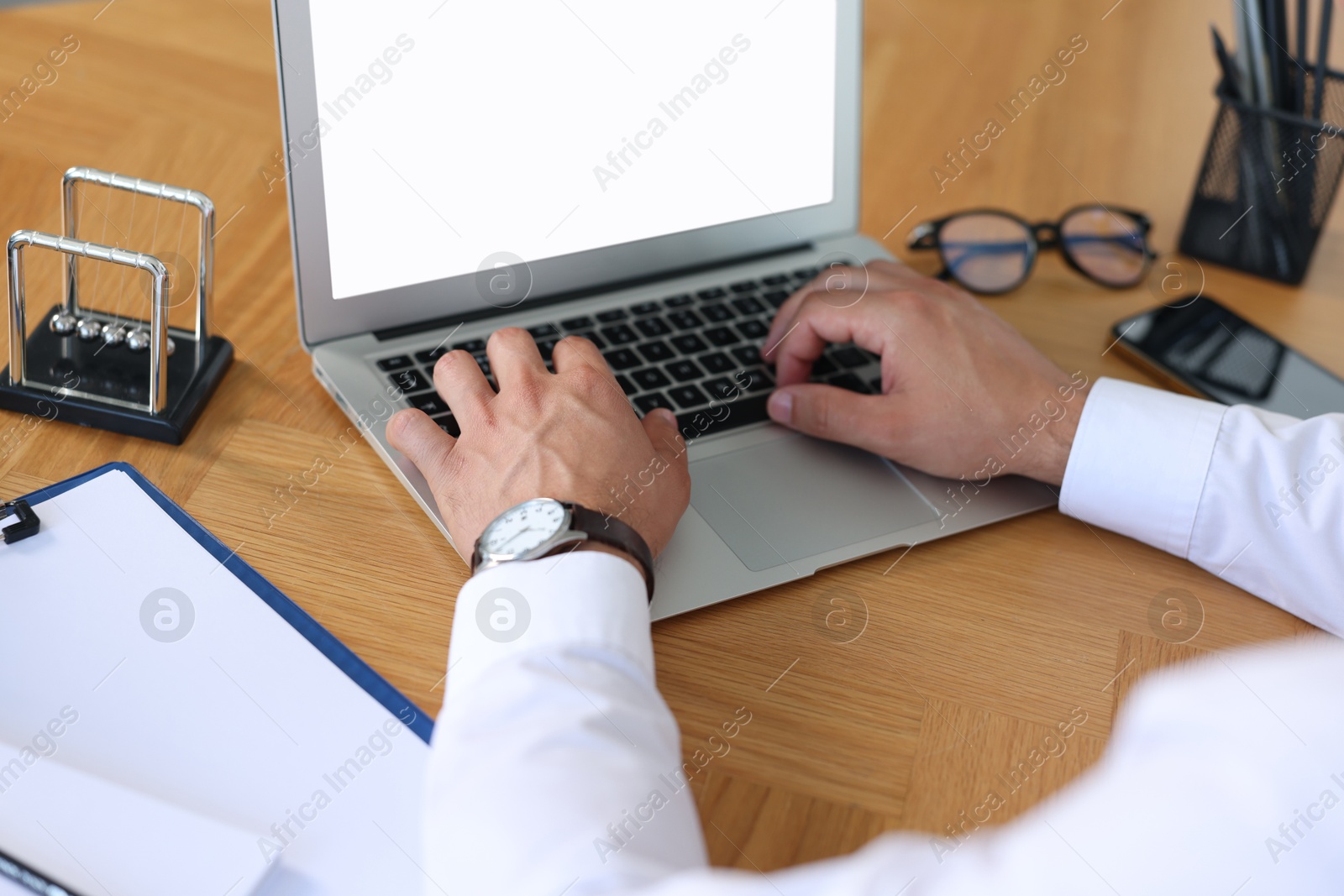 Photo of Office worker typing on laptop at wooden table, closeup