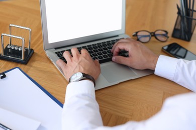 Photo of Office worker typing on laptop at wooden table, closeup