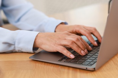 Photo of Office worker typing on laptop at wooden table, closeup