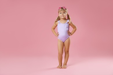 Photo of Cute little girl in beachwear with diving mask on pink background