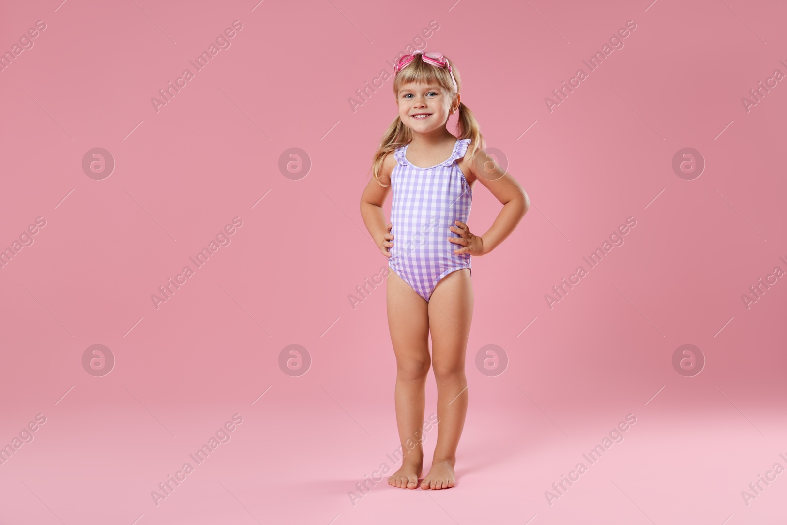 Photo of Cute little girl in beachwear with diving mask on pink background