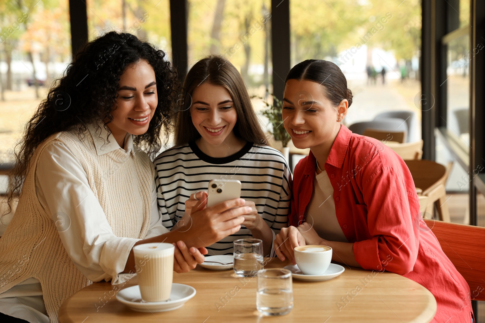 Photo of Women using smartphone while having coffee in cafe