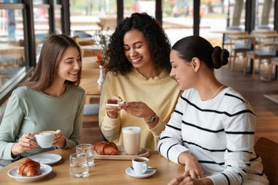 Photo of Woman taking picture of coffee drinks during meeting with her friends in cafe