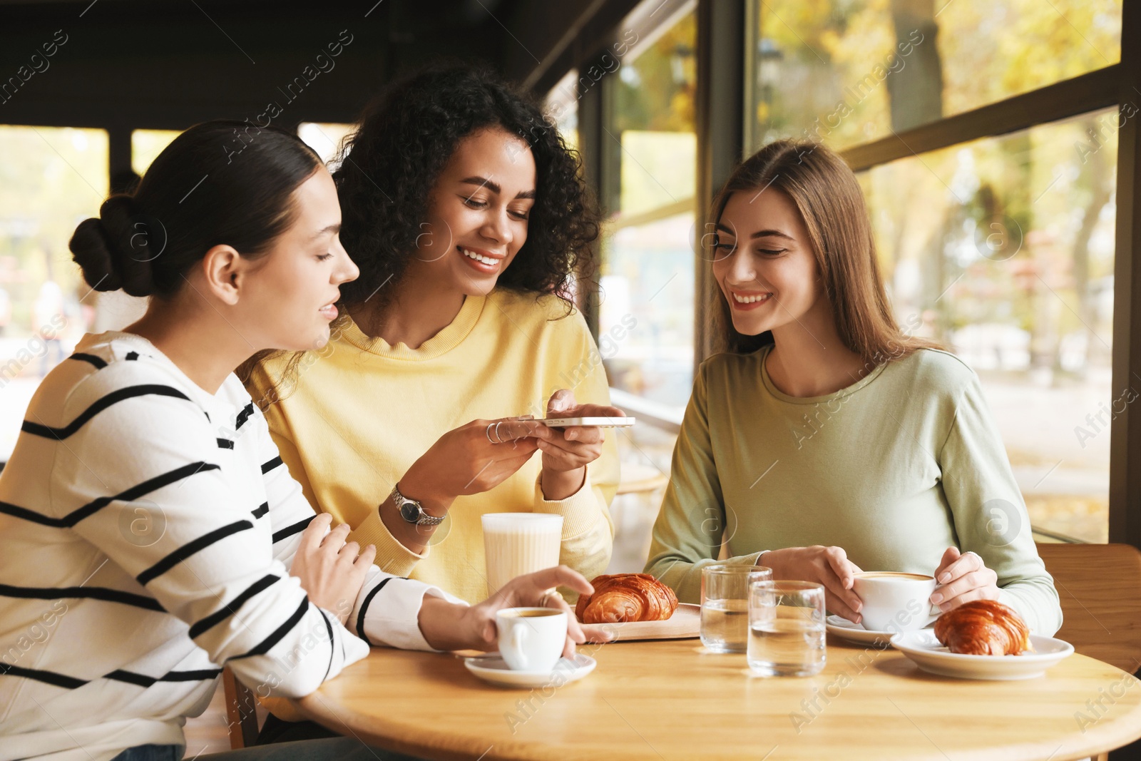 Photo of Woman taking picture of coffee drinks during meeting with her friends in cafe