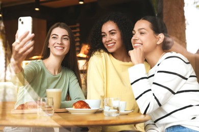 Photo of Women taking selfie at coffee meeting in cafe, view through window