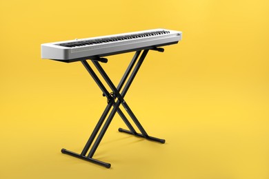 Photo of Synthesizer on yellow background, space for text. Electronic musical instrument