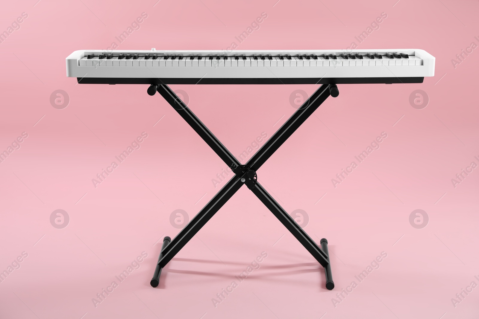 Photo of Synthesizer on pink background. Electronic musical instrument