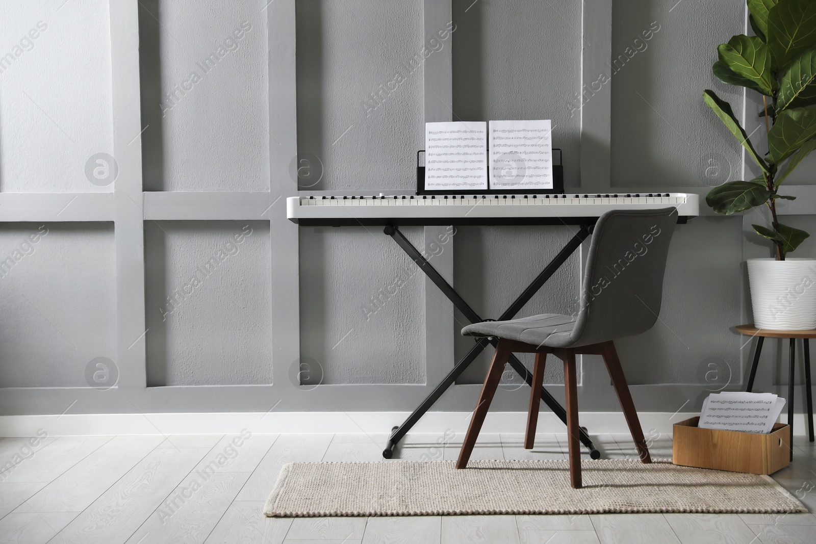 Photo of Synthesizer with music sheets and chair near grey wall indoors, space for text