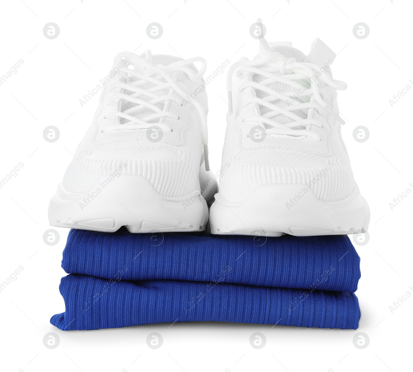 Photo of Stylish sneakers on stack of folded sportswear isolated on white