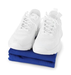 Photo of Stylish sneakers on stack of folded sportswear isolated on white