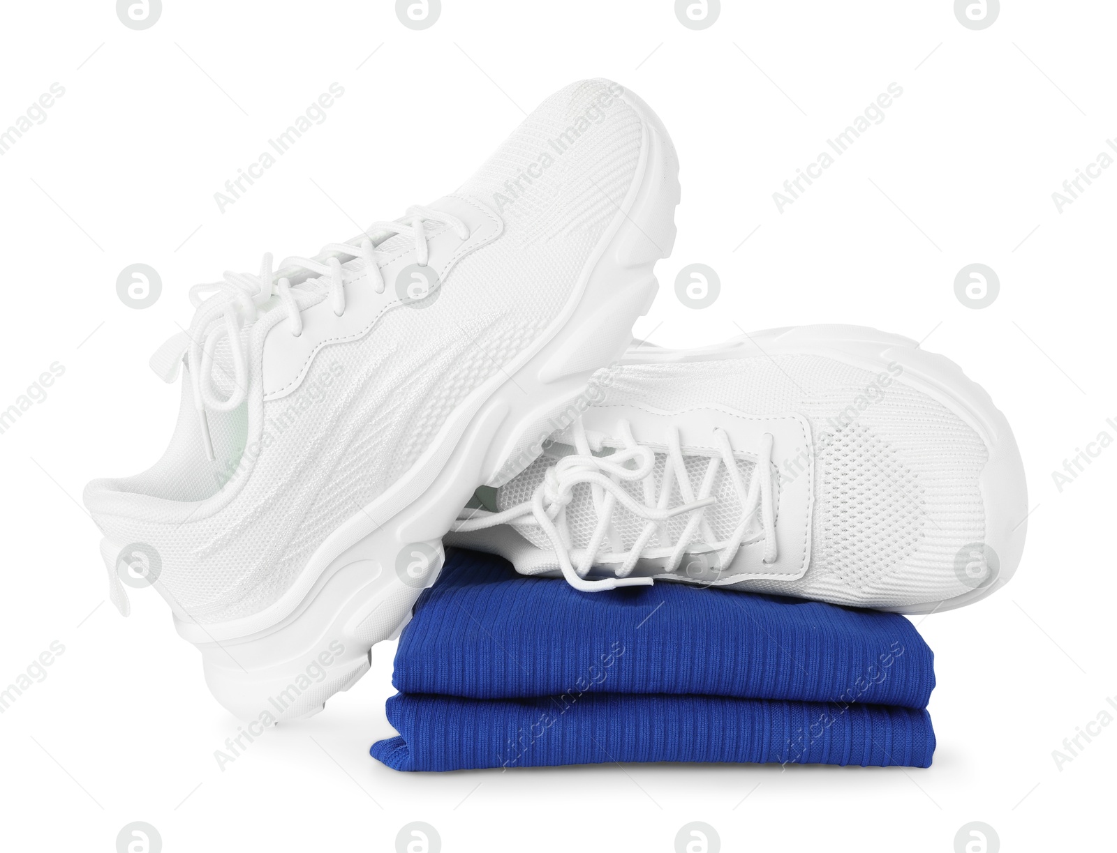 Photo of Stylish sneakers on stack of folded sportswear isolated on white