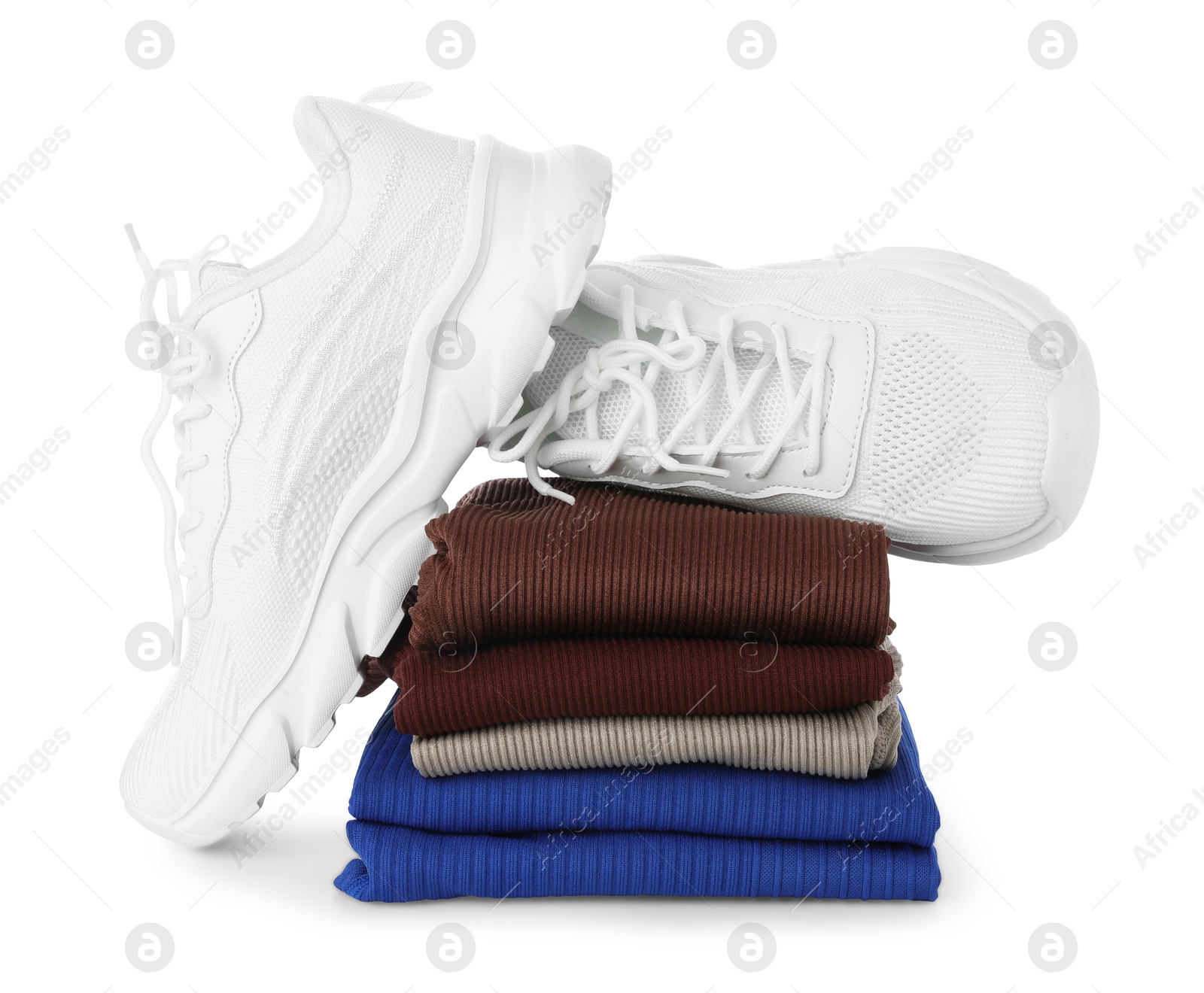 Photo of Stylish sneakers on stack of folded sportswear isolated on white