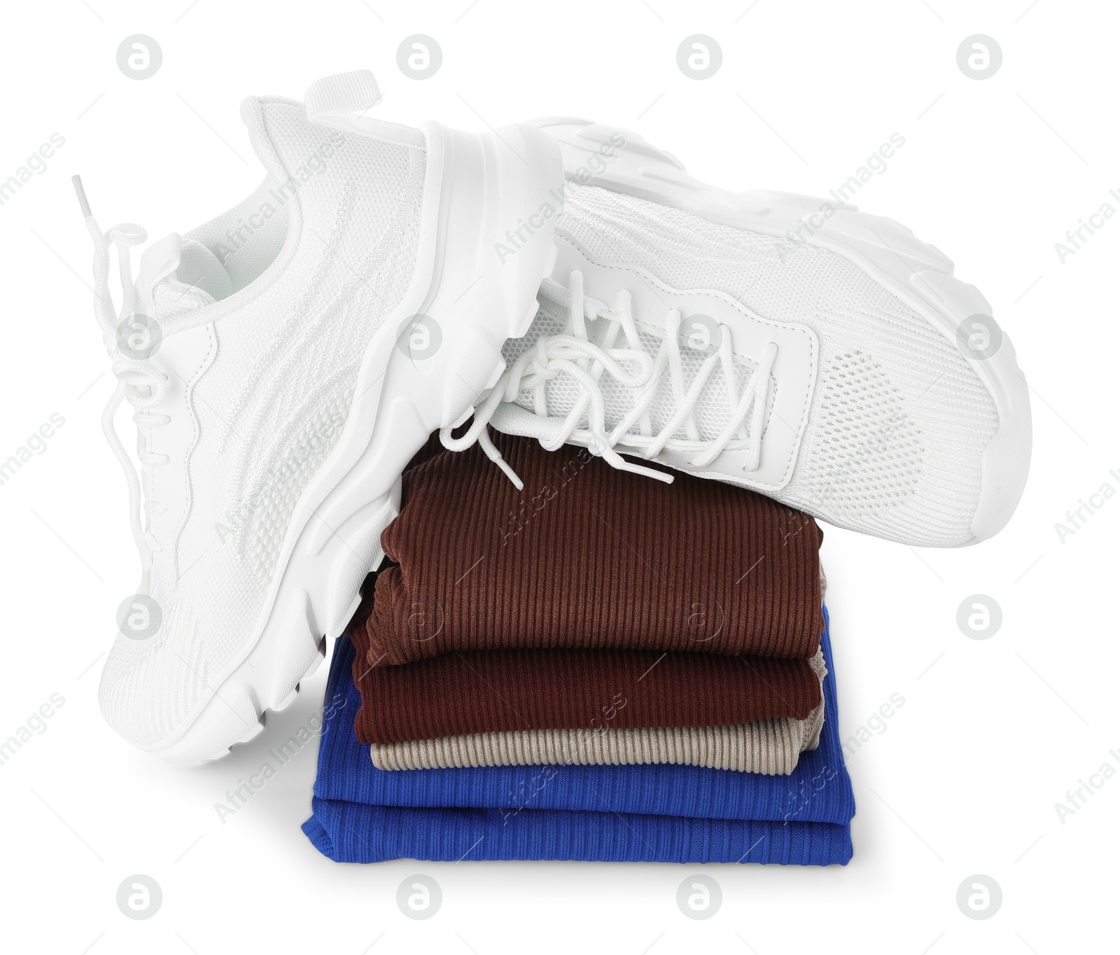 Photo of Stylish sneakers on stack of folded sportswear isolated on white