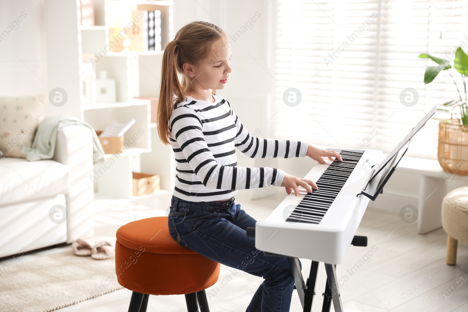 Photo of Cute girl playing synthesizer at home. Electronic musical instrument