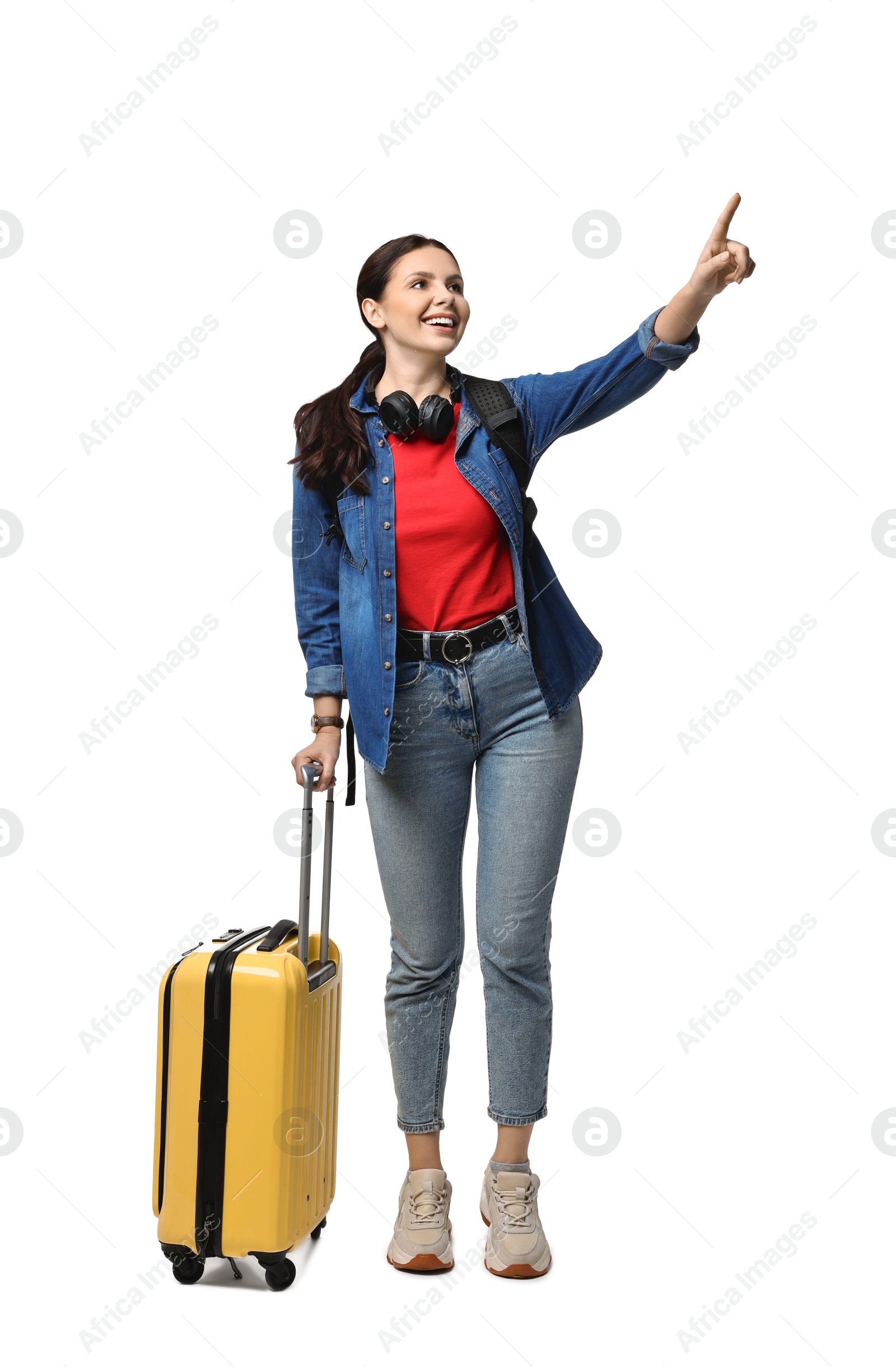 Photo of Young tourist with suitcase pointing at something on white background