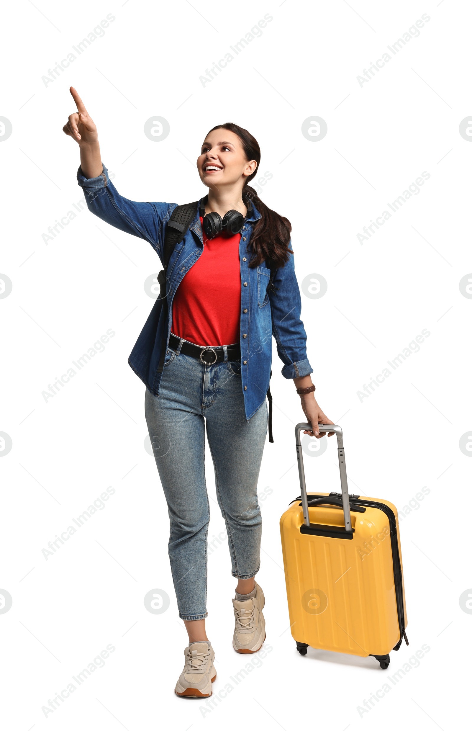 Photo of Young tourist with suitcase pointing at something on white background