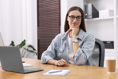 Photo of Programmer working on laptop at wooden desk indoors