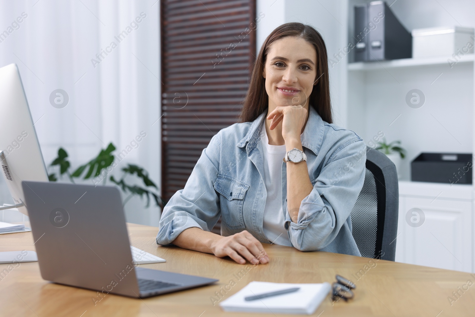 Photo of Programmer working on laptop at wooden desk indoors