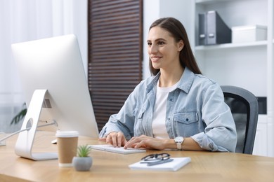 Photo of Programmer working on computer at wooden desk indoors