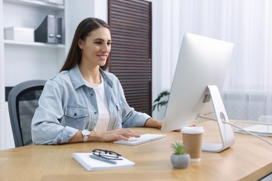 Photo of Programmer working on computer at wooden desk indoors