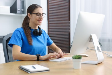 Photo of Programmer working on computer at wooden desk indoors