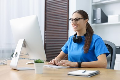 Photo of Programmer working on computer at wooden desk indoors