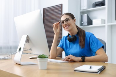 Photo of Programmer working on computer at wooden desk indoors