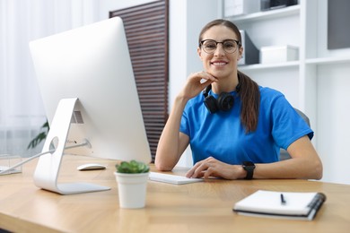 Photo of Programmer working on computer at wooden desk indoors