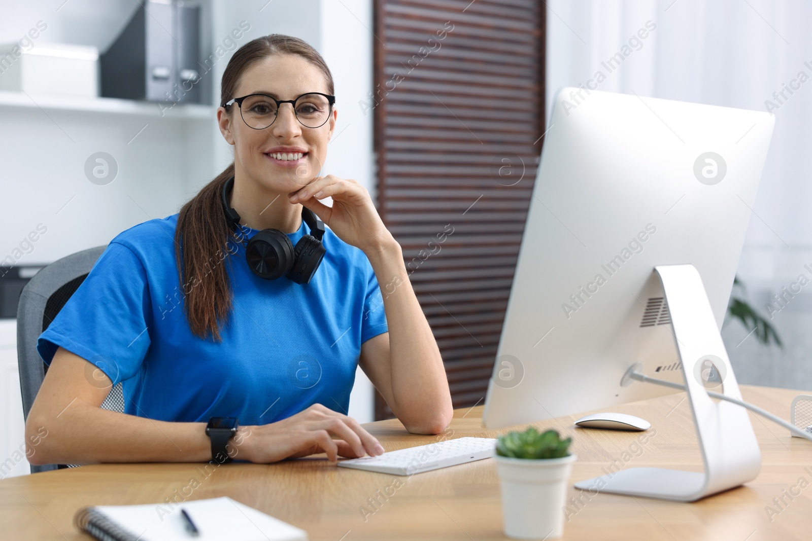 Photo of Programmer working on computer at wooden desk indoors