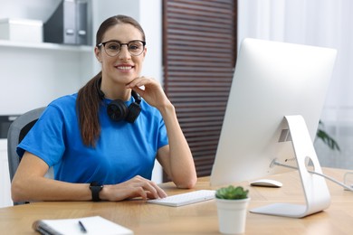 Photo of Programmer working on computer at wooden desk indoors