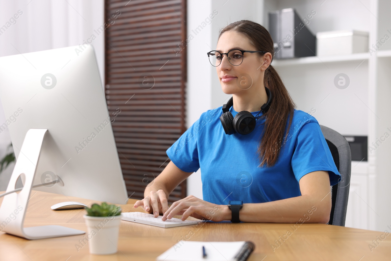 Photo of Programmer working on computer at wooden desk indoors