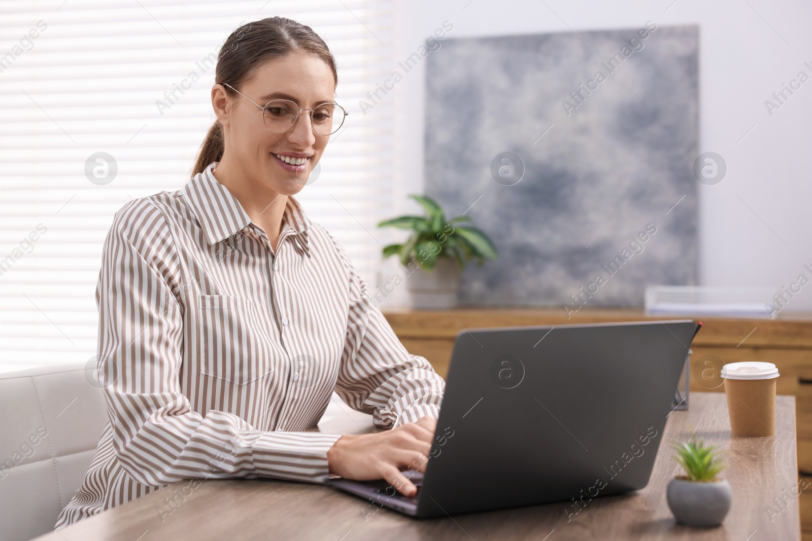 Photo of Programmer working on laptop at wooden desk indoors