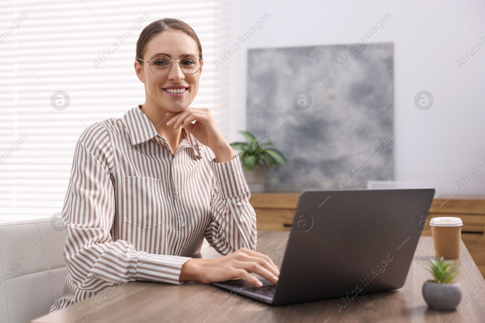 Photo of Programmer working on laptop at wooden desk indoors