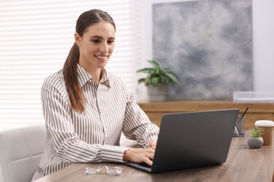 Photo of Programmer working on laptop at wooden desk indoors