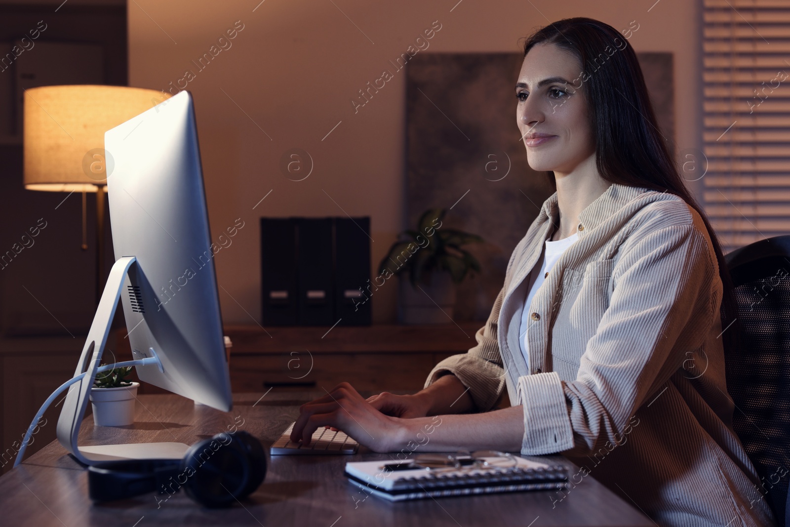 Photo of Programmer working on computer at wooden desk indoors