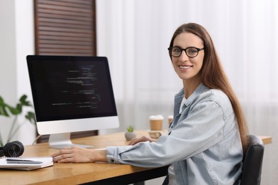 Photo of Programmer working on computer at wooden desk indoors