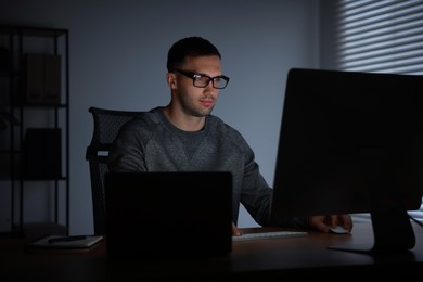 Photo of Programmer working on computer indoors at night