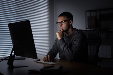 Photo of Programmer working on computer indoors at night