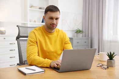 Photo of Programmer working on laptop at wooden desk indoors